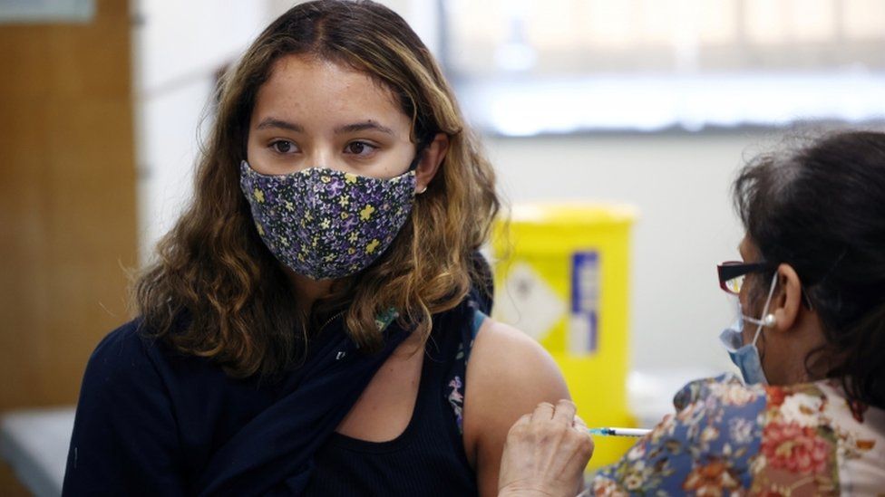 A person receives a dose of the Pfizer-BioNTech vaccine at a vaccination centre for those aged over 18 years old at the Belmont Health Centre in Harrow