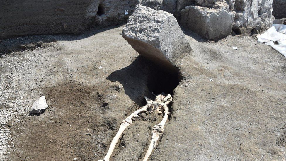 The skeleton of a victim of the eruption that destroyed Pompeii, shown with a huge boulder where his head should be