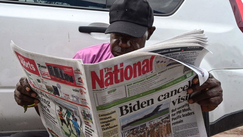 Un uomo legge un giornale che riporta la notizia dell'annullamento della visita in Papua Nuova Guinea del Presidente degli Stati Uniti Joe Biden a Port Moresby il 18 maggio 2023.