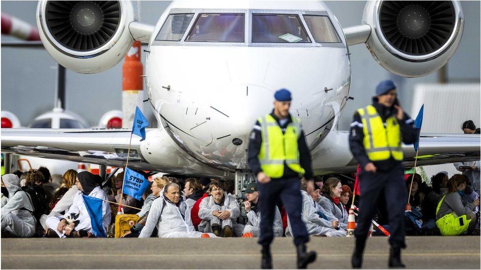 Demonstrators sitting under a private jet at Schiphol Airport on 5 November