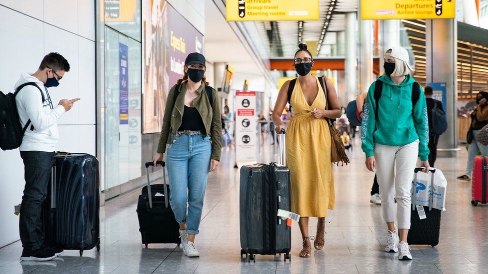 Three women in masks arriving at Heathrow