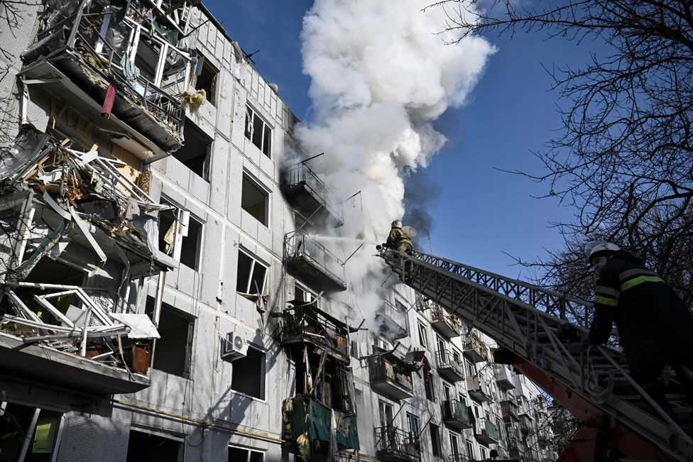 Firefighters work on a fire on a building after bombings on the eastern Ukraine town of Chuguiv on 24 February 2022