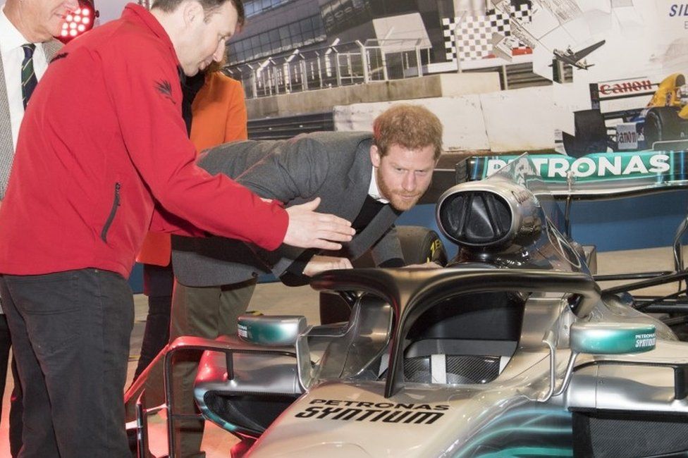 Prince Harry, studies the "Halo" on Lewis Hamilton"s Mercedes, a new safety addition to Formula 1 cars this year, during a visit to the Silverstone Circuit in Northamptonshire