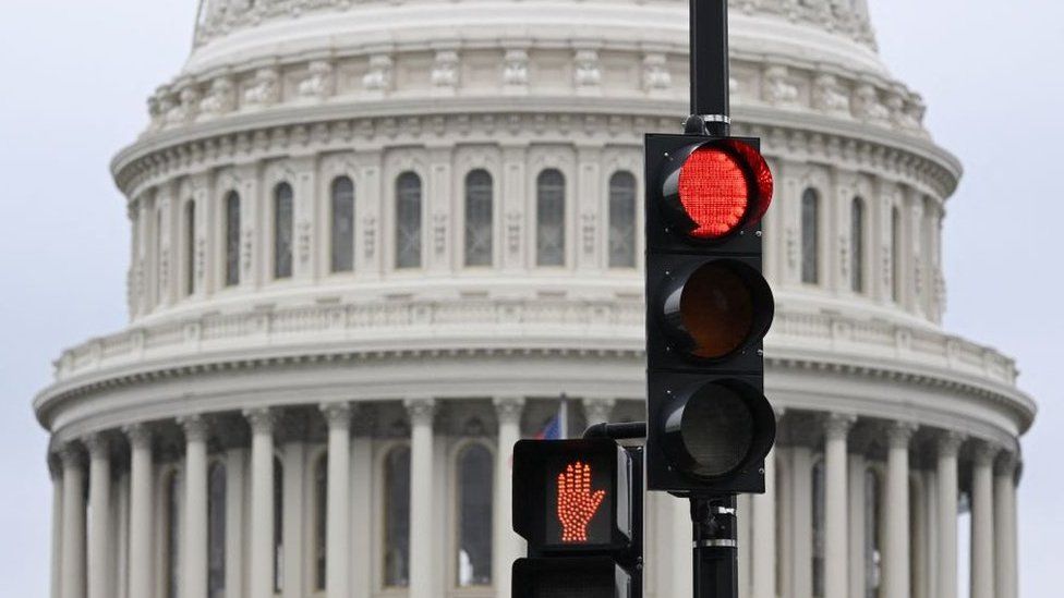 A stoplight is seen in front of the dome of the US Capitol