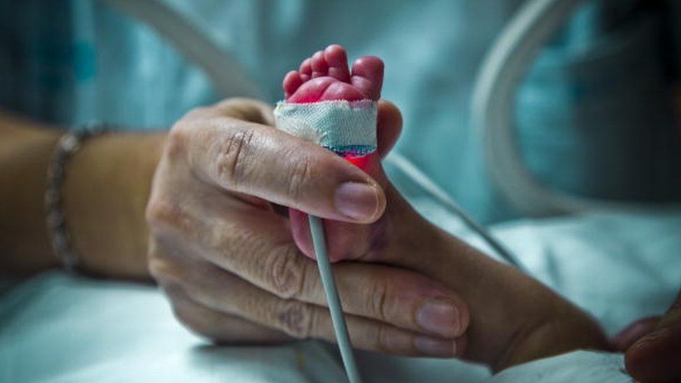 A parent holding a premature baby's foot