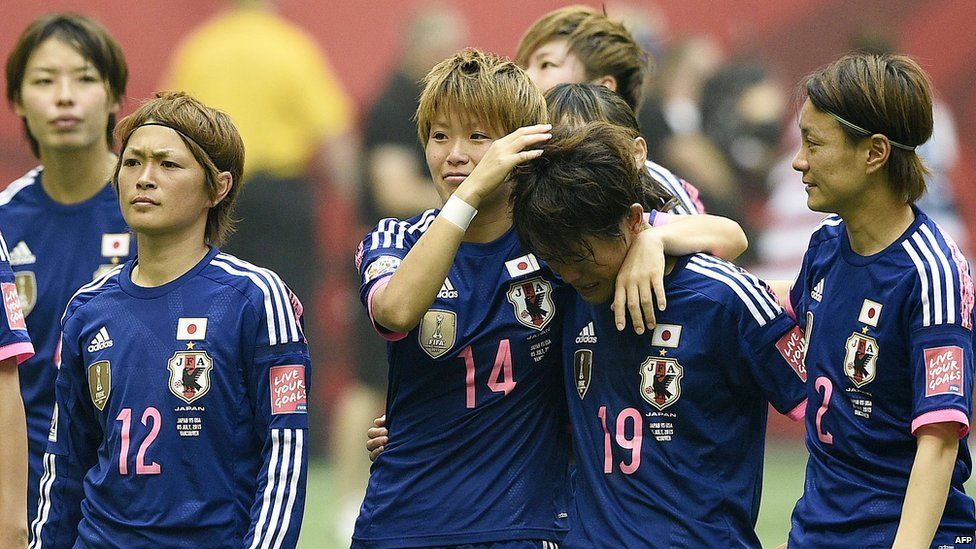Japan's players stand on the pitch after losing the final football match between USA and Japan on 5 July, 2015