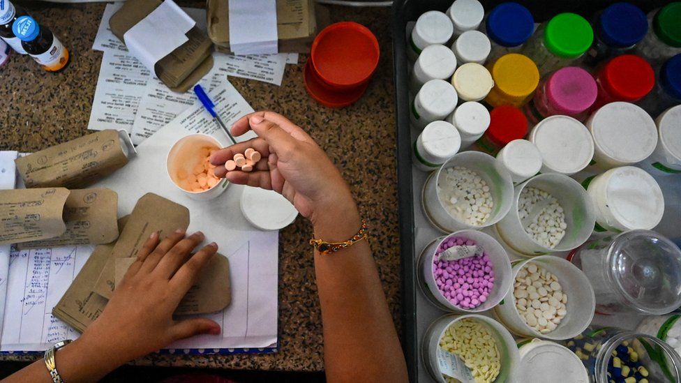 A Sri Lankan health workers is seen dispensing medicines into a container