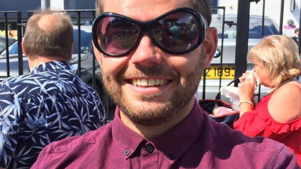 Dean McIlwaine smiling while wearing a pair of sunglasses