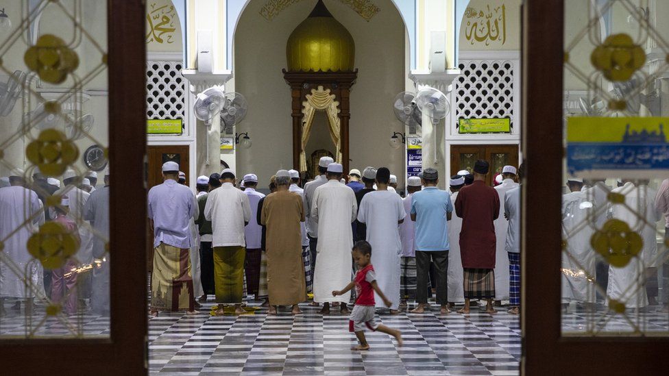 Thai men attend the evening prayer as a boy runs across the floor at the Pattani Central mosque, in Pattani, Thailand.