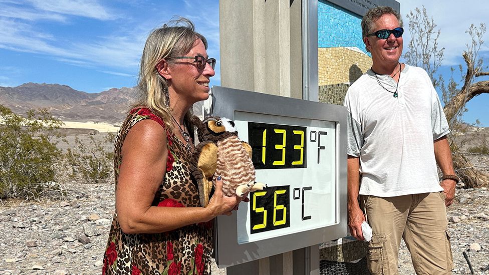 People pose for pictures with a thermometer showing temperatures reaching 133 F, in Death Valley, California, U.S. July 16, 2023