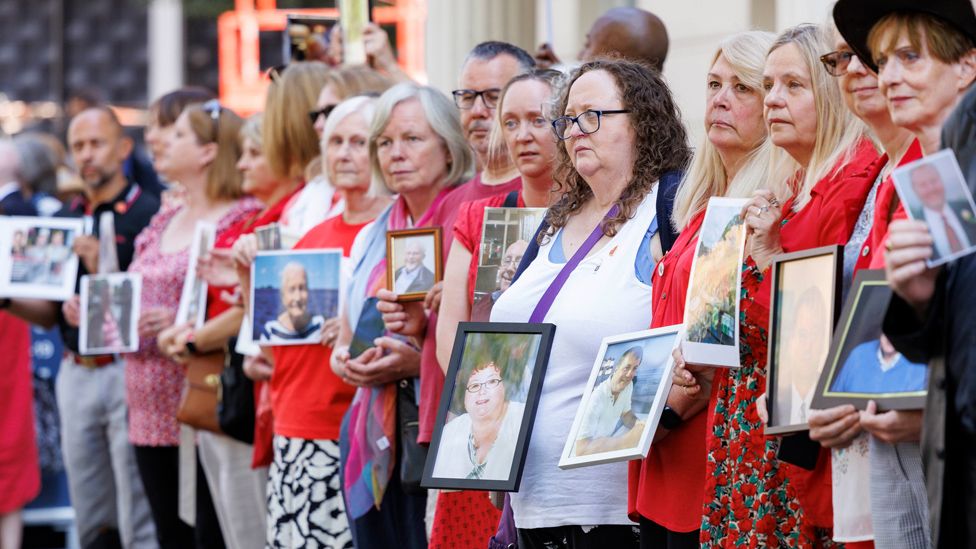People hold pictures of loved ones lost during the pandemic outside the UK Covid-19 Inquiry