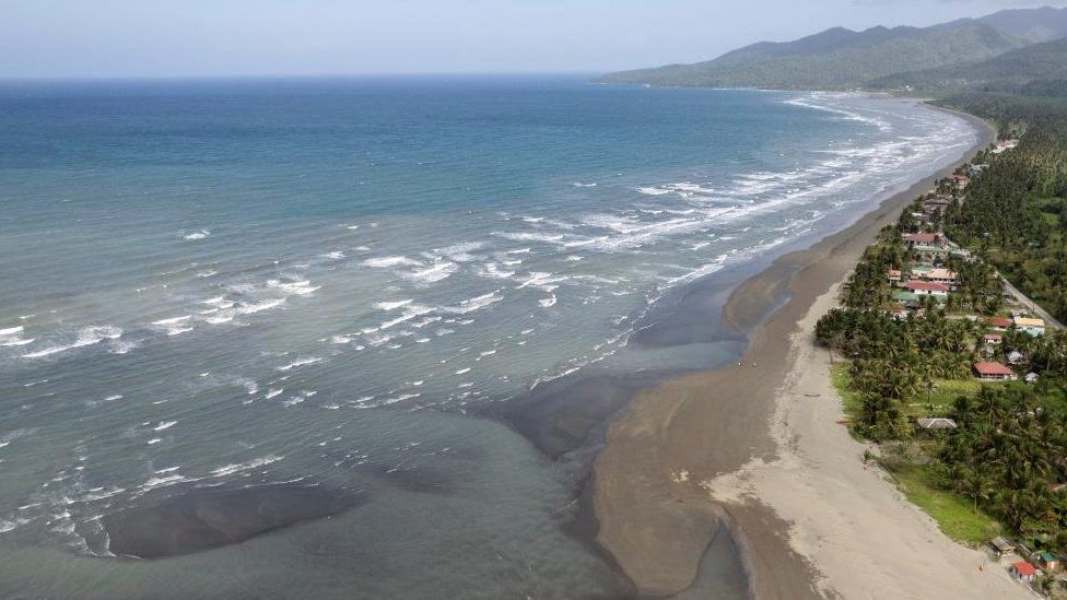 An aerial view of an oil spill that has hit the beaches of a coastal town