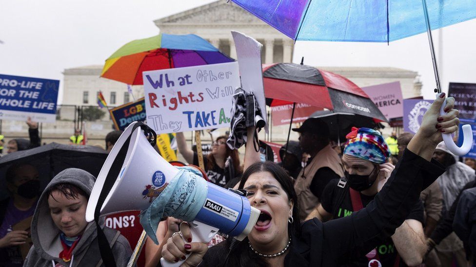 Активист против абортов (Фронт) кричит в мегафон перед активистами за права абортов позади в Верховном суде