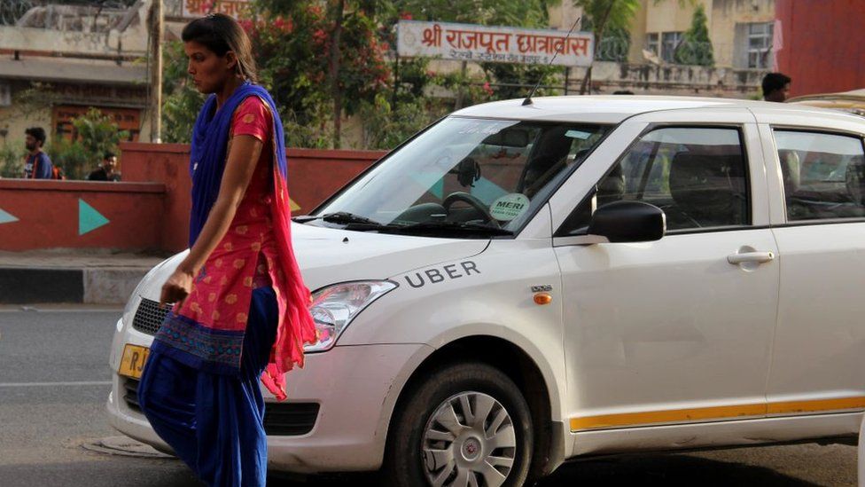 A lady walks past an Uber cab in India
