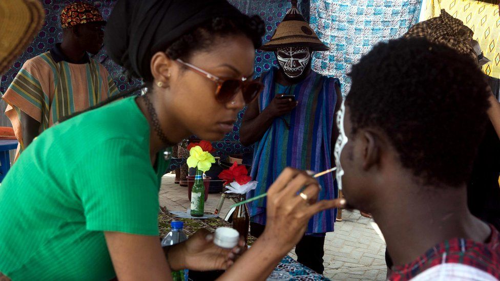 An artist paints the face of a man during the Chale Wote street art festival in Accra, on August 21, 2016