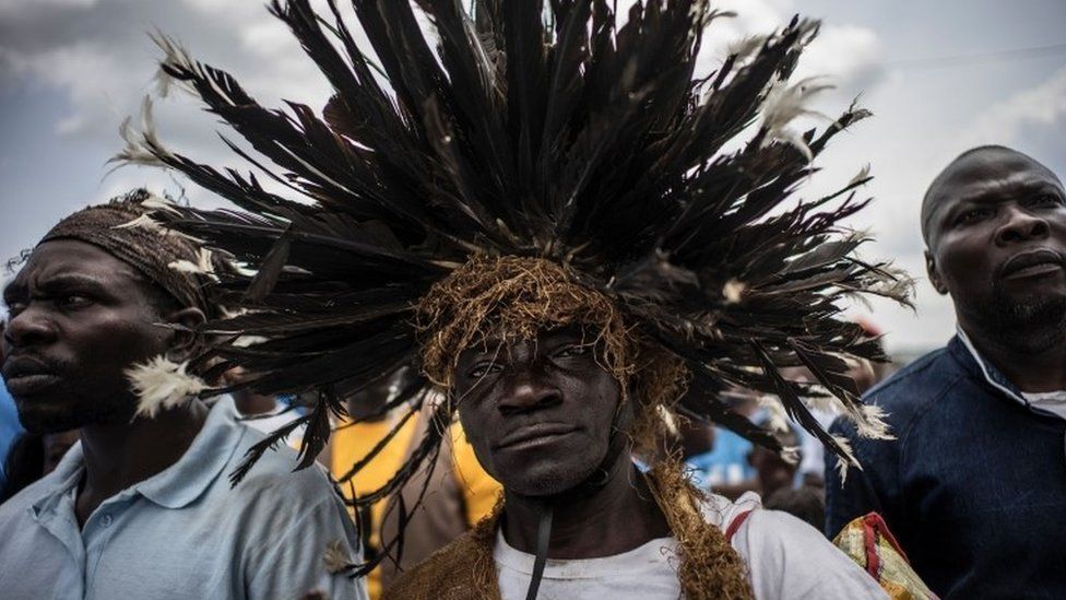 A man wearing a traditional Bateke feathered wig joins supporters of incumbent Gabonese President Ali Bongo Ondimba at an electoral rally in Lekoni on 23 August 2016