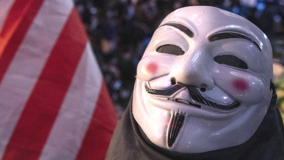An Anonymous mask is seen next to a US flag in this photograph, which was actually taken in Hong Kong during the pro-democracy protest there in 2019