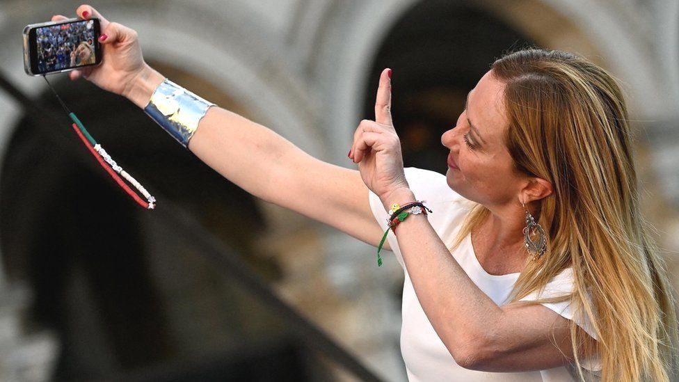 Giorgia Meloni, leader of the far-right Brothers of Italy party, takes a selfie during a rally