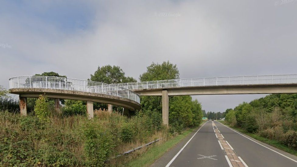 Concrete footbridge over main road with white railings