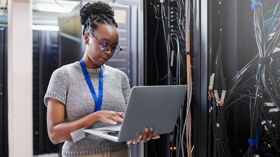 A black woman working in a server room