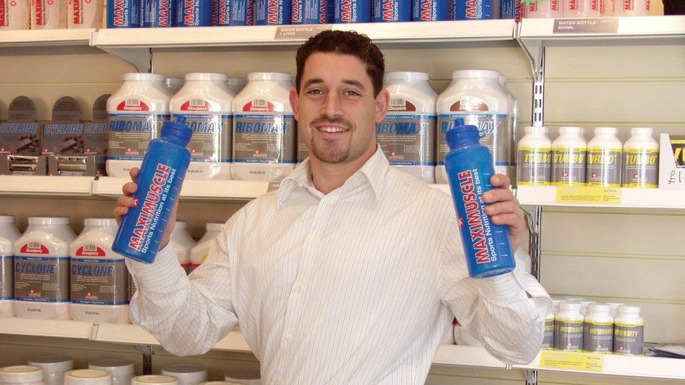 Zef Eisenberg holding Maximuscle bottles in 2002