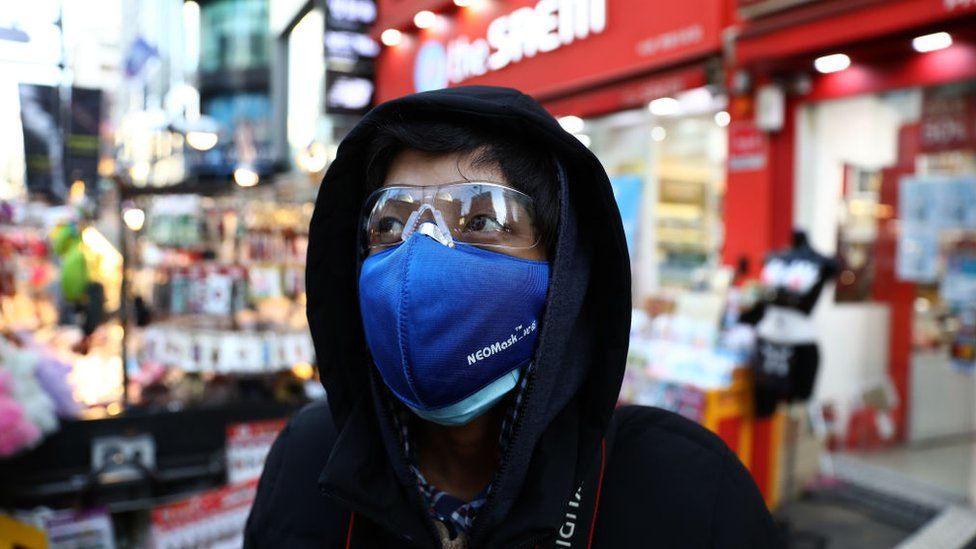 A man wear mask to prevent the coronavirus (COVID-19) walk along the Myungdong shopping district on February 23, 2020
