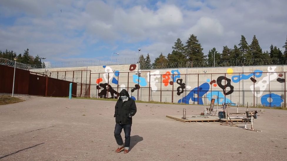 Artist EGS in a Finnish prison yard in front of a mural by him.