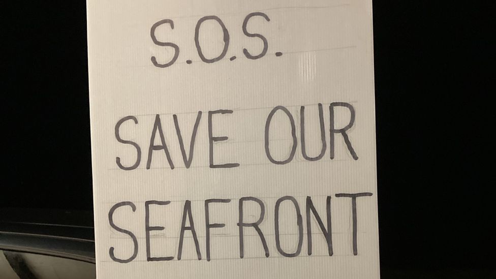 A sign attached to a lamppost reads: Save Our Seafront