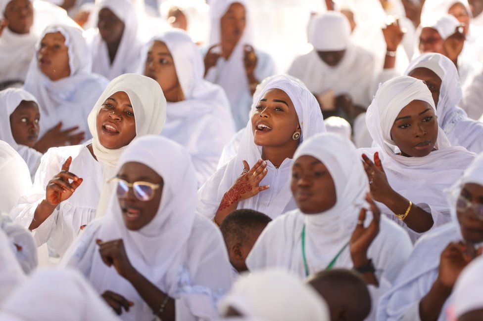 Members of the Layene Brotherhood sit and sing together, dressed in all white, in Dakar.
