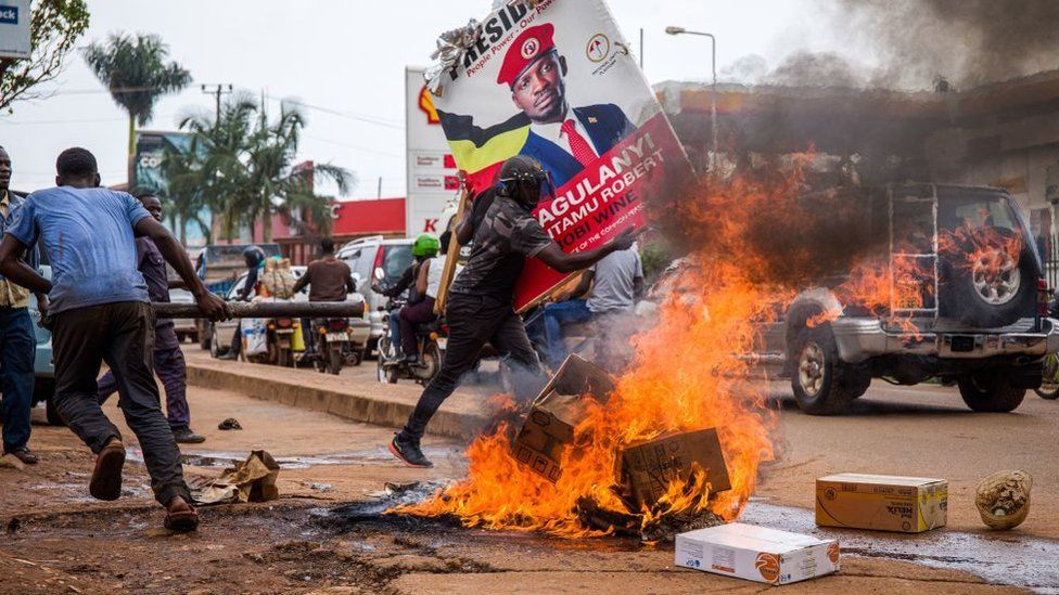 A supporter of Ugandan musician turned politician Robert Kyagulanyi, also known as Bobi Wine, carries his poster as they protest on a street against the arrest of Kyagulanyi