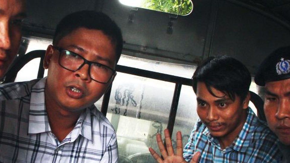 Wa Lone, left, and Kyaw Soe Oo gesture to the camera wearing handcuffs after their arrest in 2018
