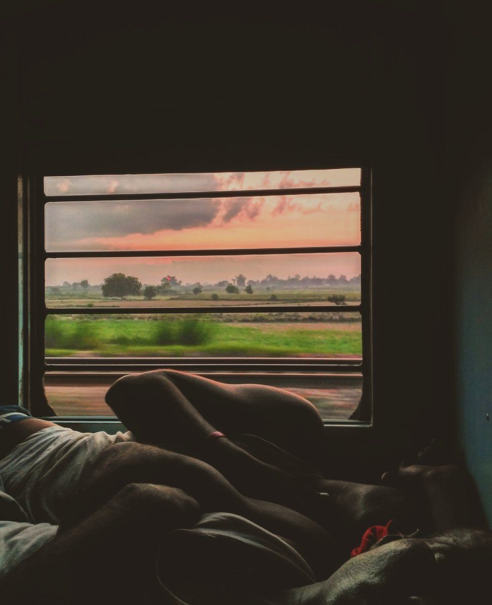 Two men sleep next to each other on a lower berth.