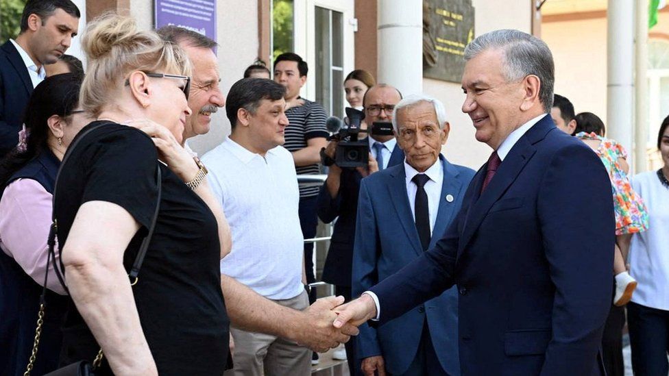 Uzbekistan's President Shavkat Mirziyoyev is greeted at a local polling station