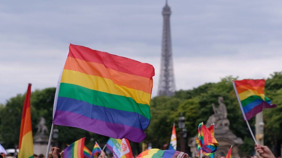 An LGBT flag flies in front of the Eiffel Tower