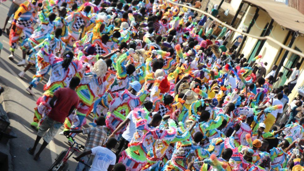 large groups dressed in multi-coloured costumes parade through the city centre in Sekondi Ghana