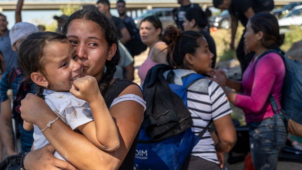 A woman with a young child looks emotional after crossing the US-Mexico border