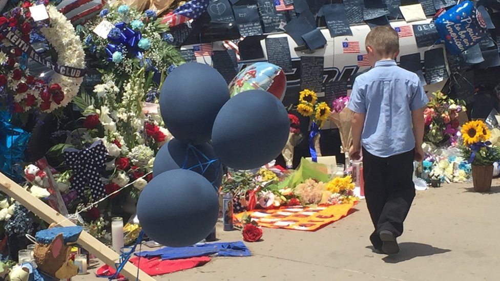 Boy looks at flowers in front of Dallas police HQ (10 July)