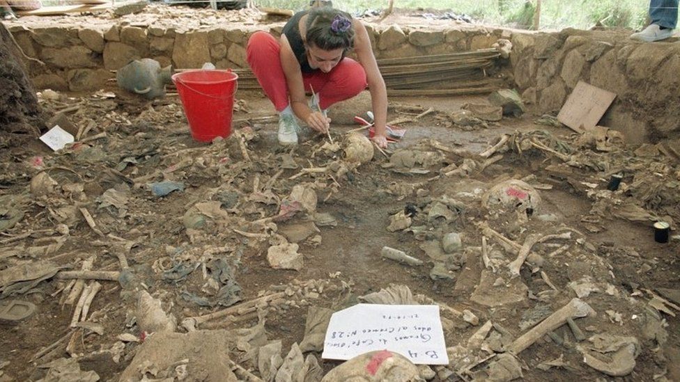 Forensic anthropologist Claudia Bernard brushes dirt from human remains in El Mozote, El Salvador (October 1992)