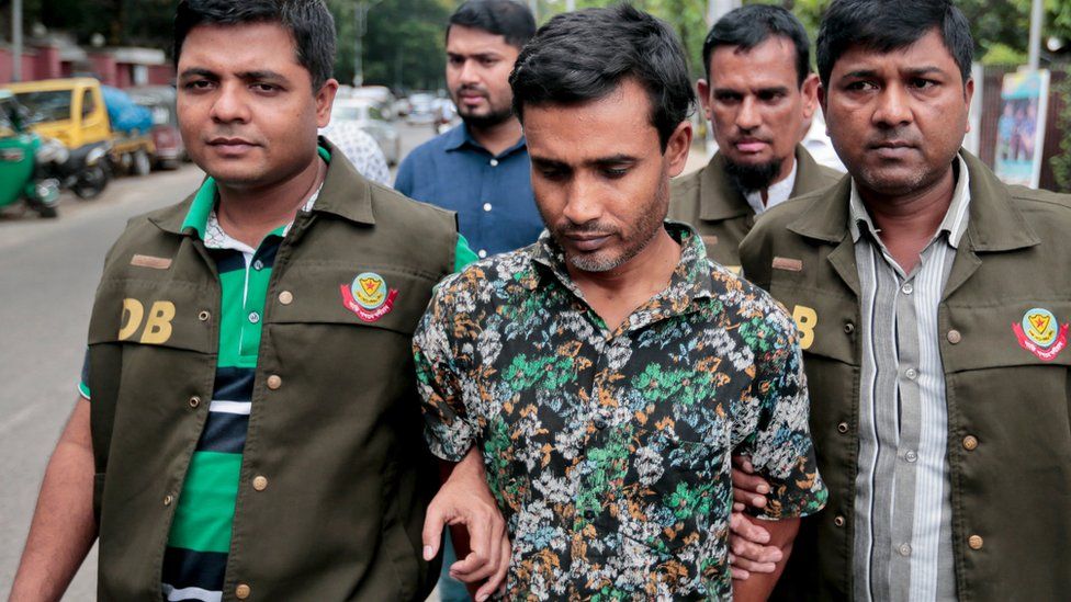 Members of Bangladesh Police Detective Branch (DB) escort a man, center, whom they have identified as Shariful Islam Shihab, a former member of the banned Islamic group Harkatul Jihad as they walk him in front of the media in Dhaka, Bangladesh, Sunday, May 15,