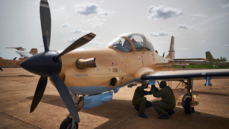 Two mechanics prearrange one of the four newly arrived turboprop light attack aircrafts 'Super Tucano' at the military air base in Bamako on July 11, 2018.