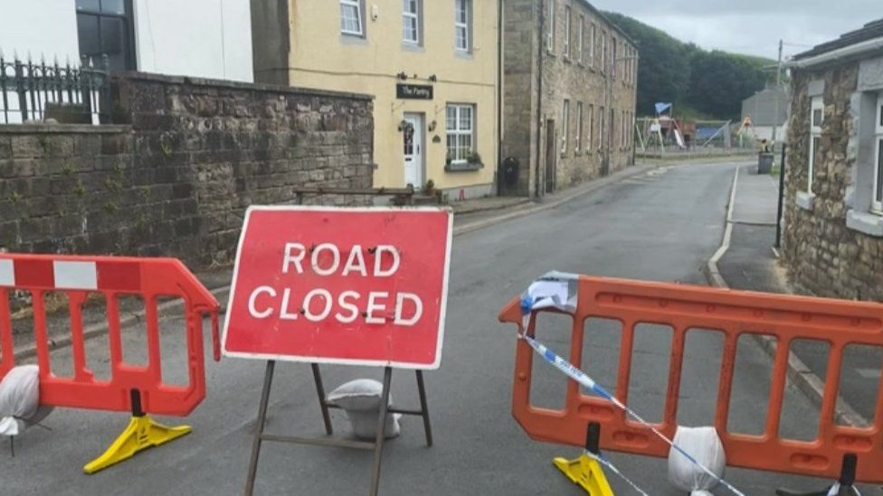 Road closed sign on Main Street in Parton and barriers