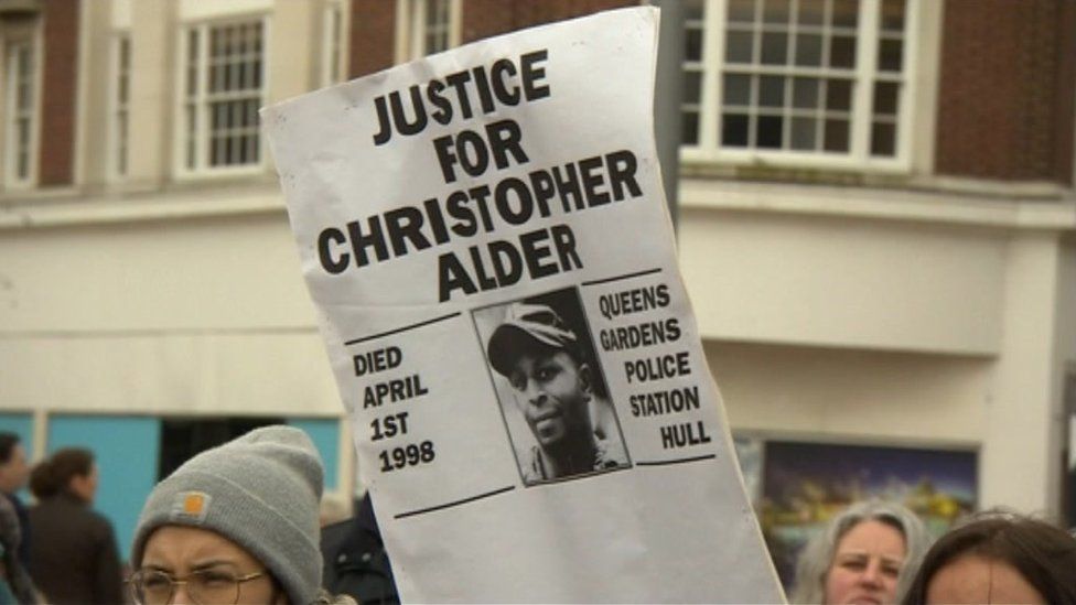 People holding a placard reading: 'Justice for Christopher Alder'