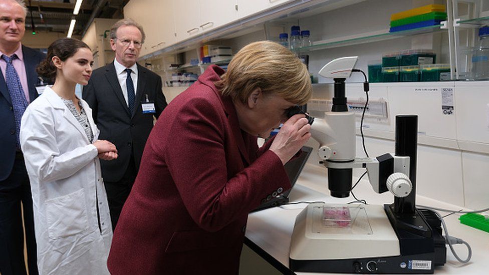 Канцлер Германии Ангела Меркель смотрит в микроскоп