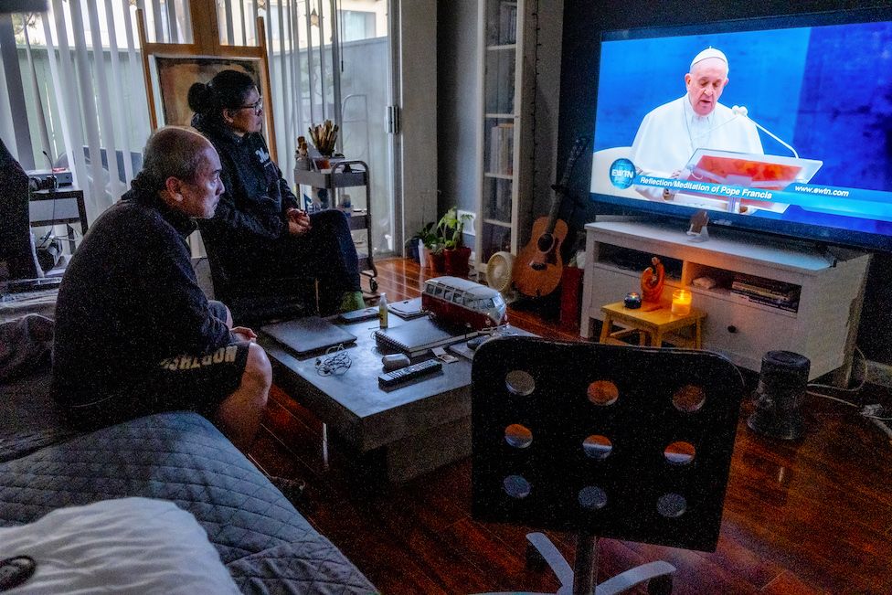 Miguel's family watches the Pope give a blessing on TV