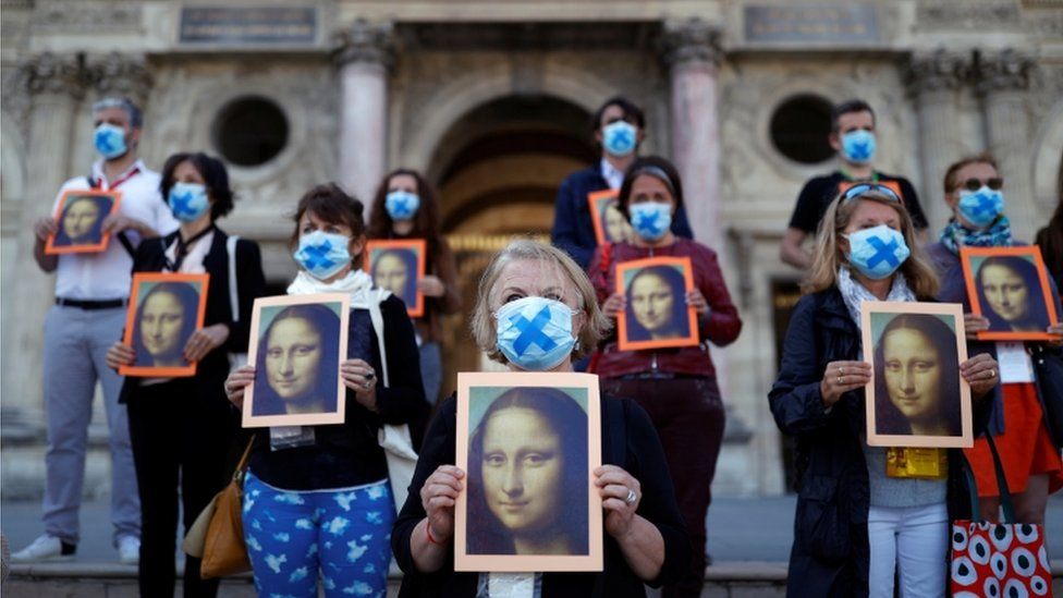 Demonstrators outside the Louvre holding copies of the Mona Lisa