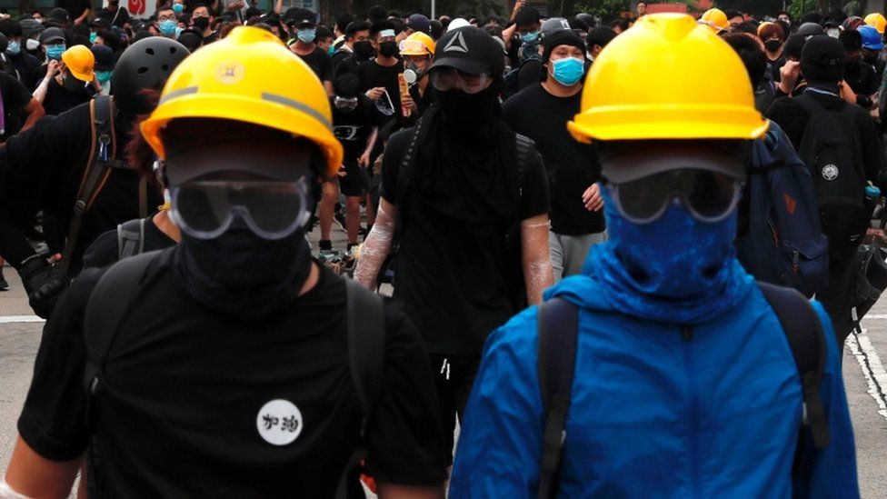 Two protesters wear yellow hard hats during protests in Hong Kong