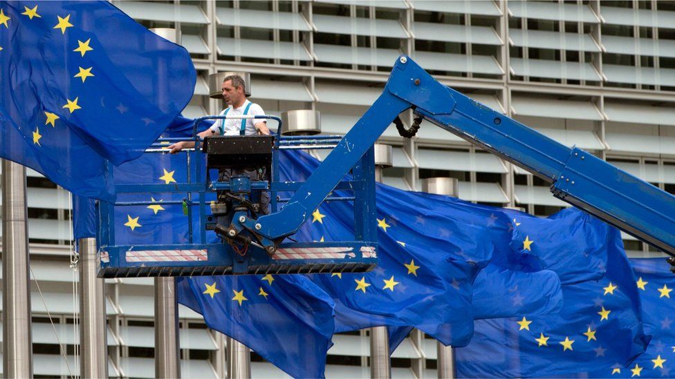 A worker on a lift adjusts the EU flags in front of EU headquarters in Brussels (June 22, 2016)
