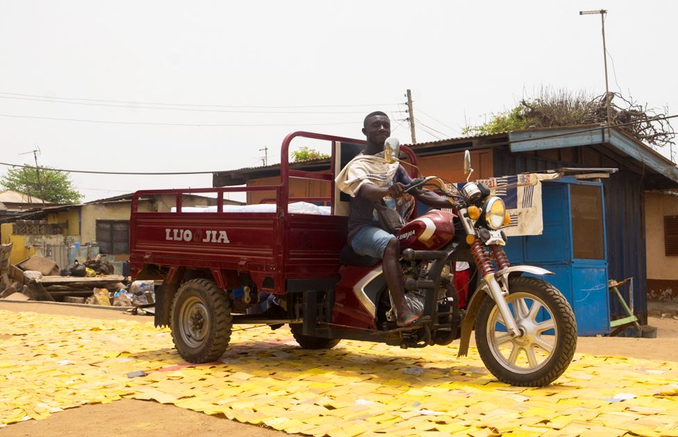 A vehicle on a yellow tapestry created by artist Serge Attukwei Clottey on a road in La - Accra, Ghana