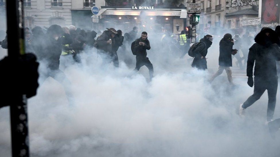 Protesters run away from tear gas during a demonstration in Paris, on January 11, 2020