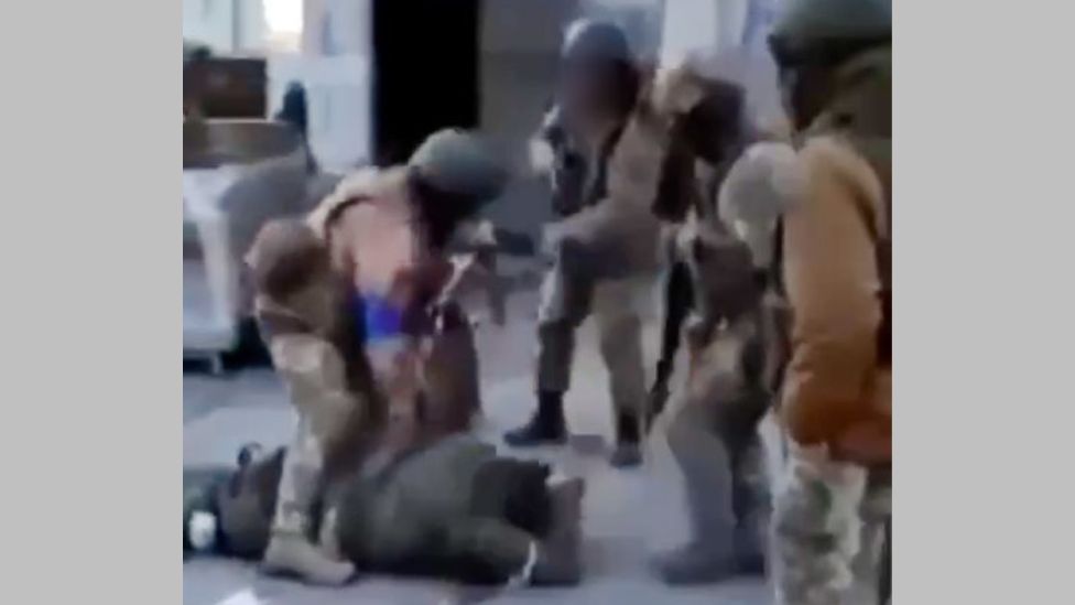 Még mindig a videóból, amelyen egy kék karszalagot viselő katona látható